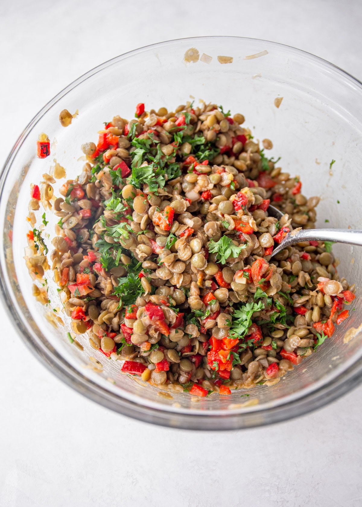 stirring lentil salad in a clear glass jar