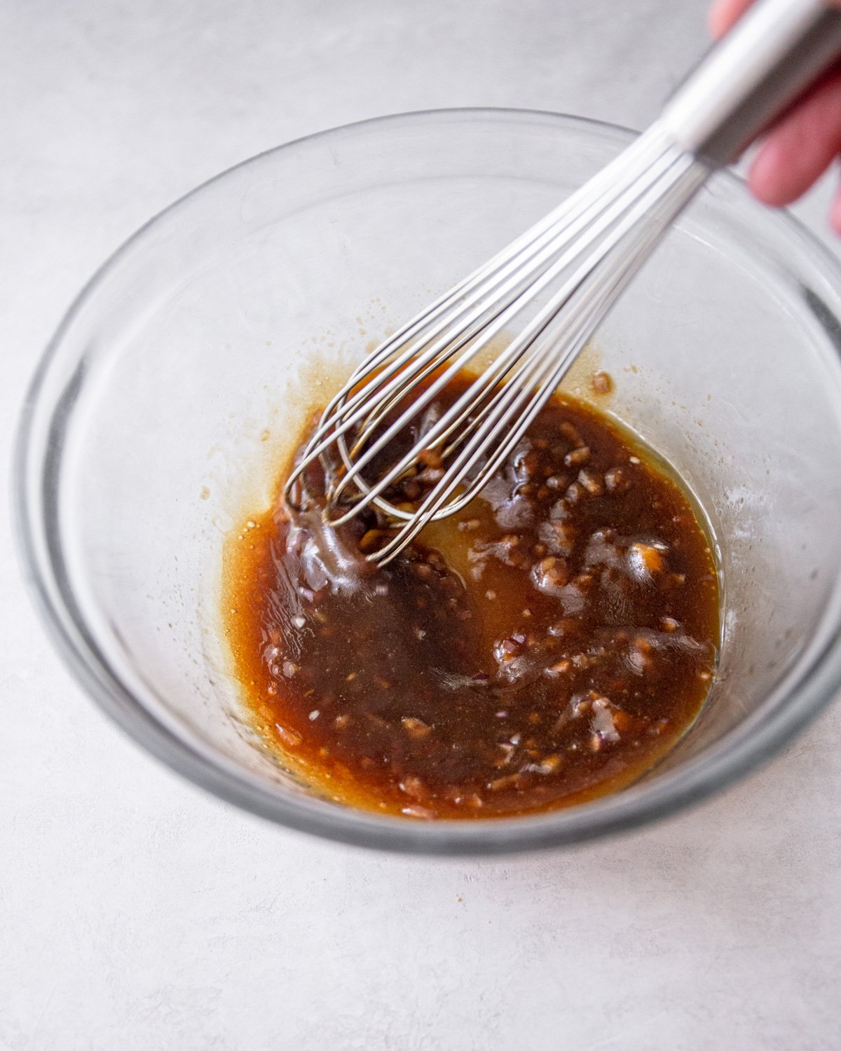 stirring balsamic vinaigrette in a clear glass bowl