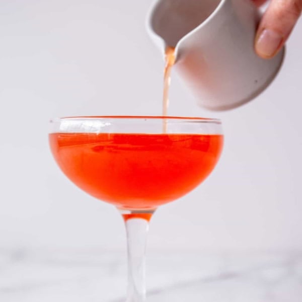 small glass of pink cocktail in a white background