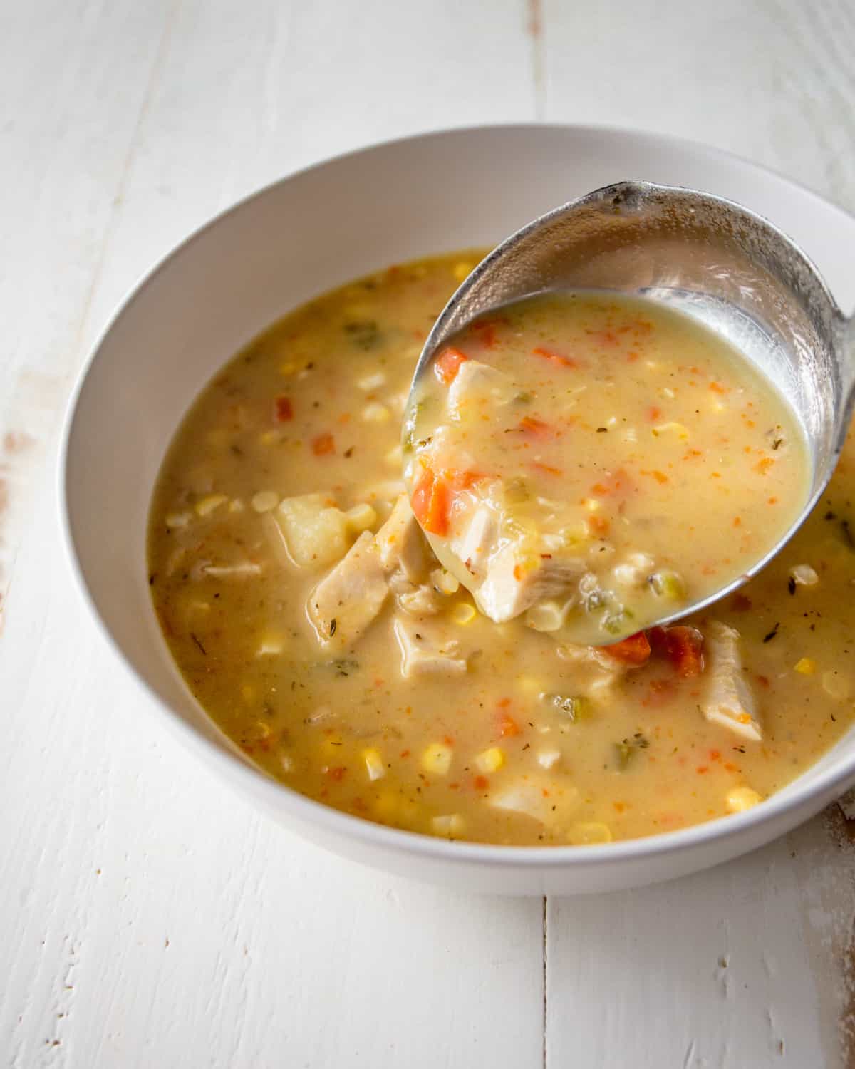 ladling instant pot chicken chowder into a white bowl