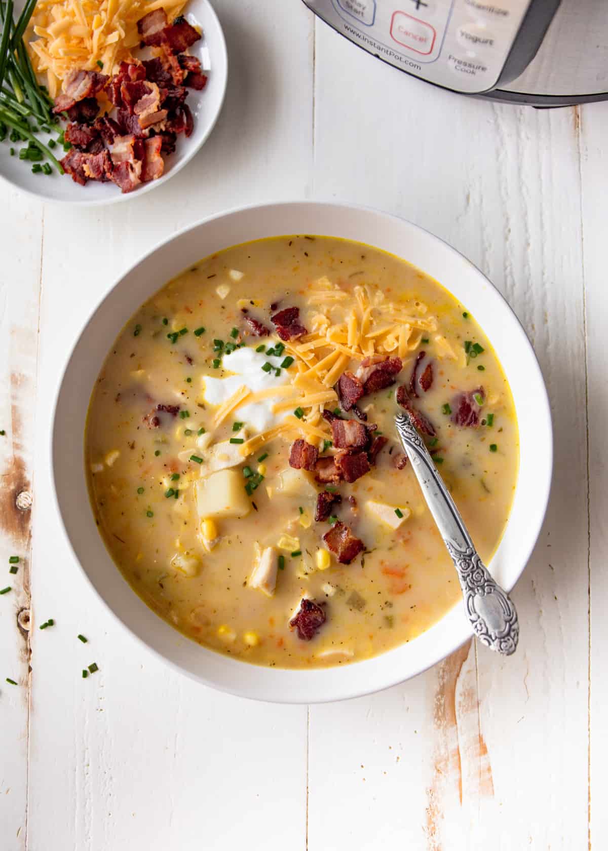 chicken chowder in a white bowl, topped by cheese and sour cream