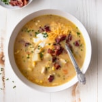 uma tigela de sopa de milho de frango em uma mesa branca