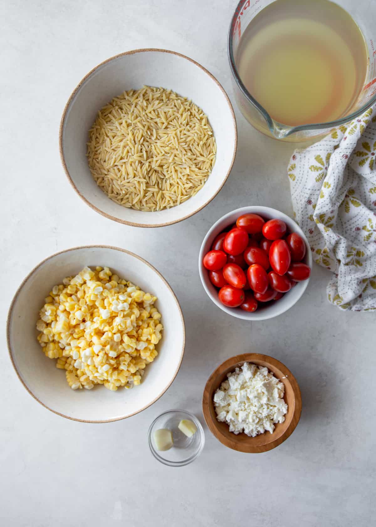 ingredientes para um pote orzo com queijo feta em uma bancada cinza