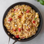 a skillet with orzo and vegetables sitting on a gray countertop