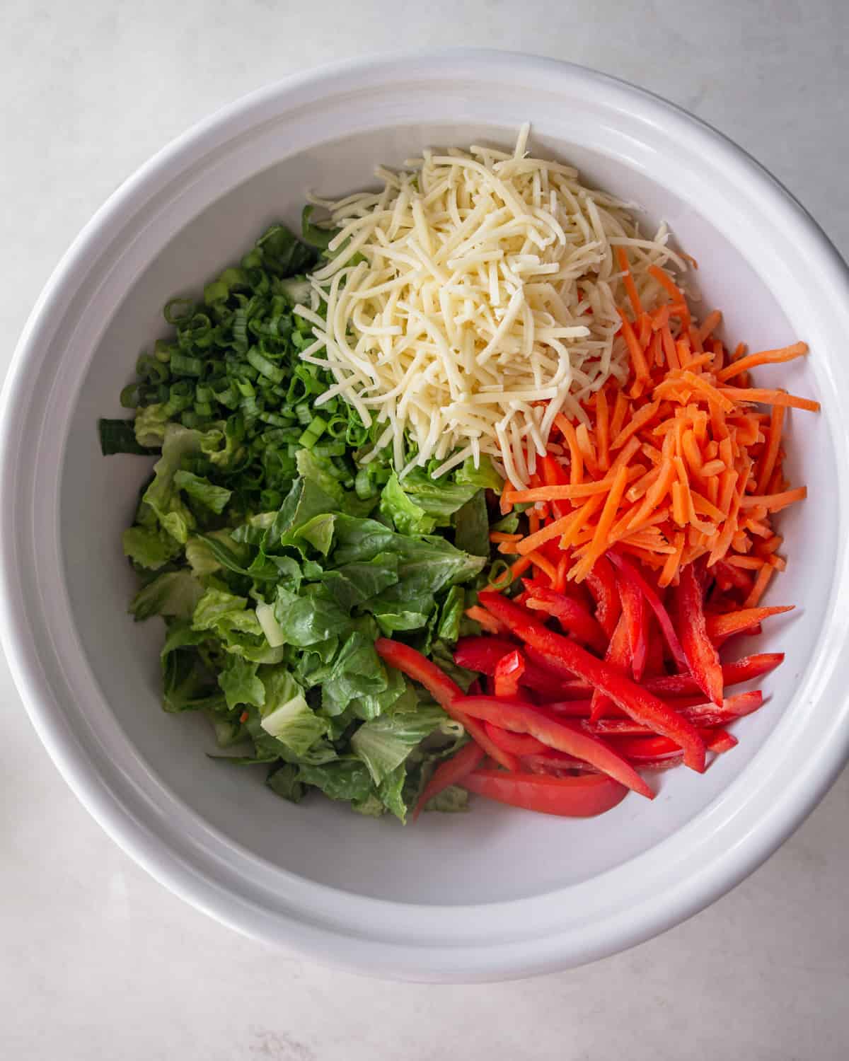peppers, lettuce and cheese in a white mixing bowl
