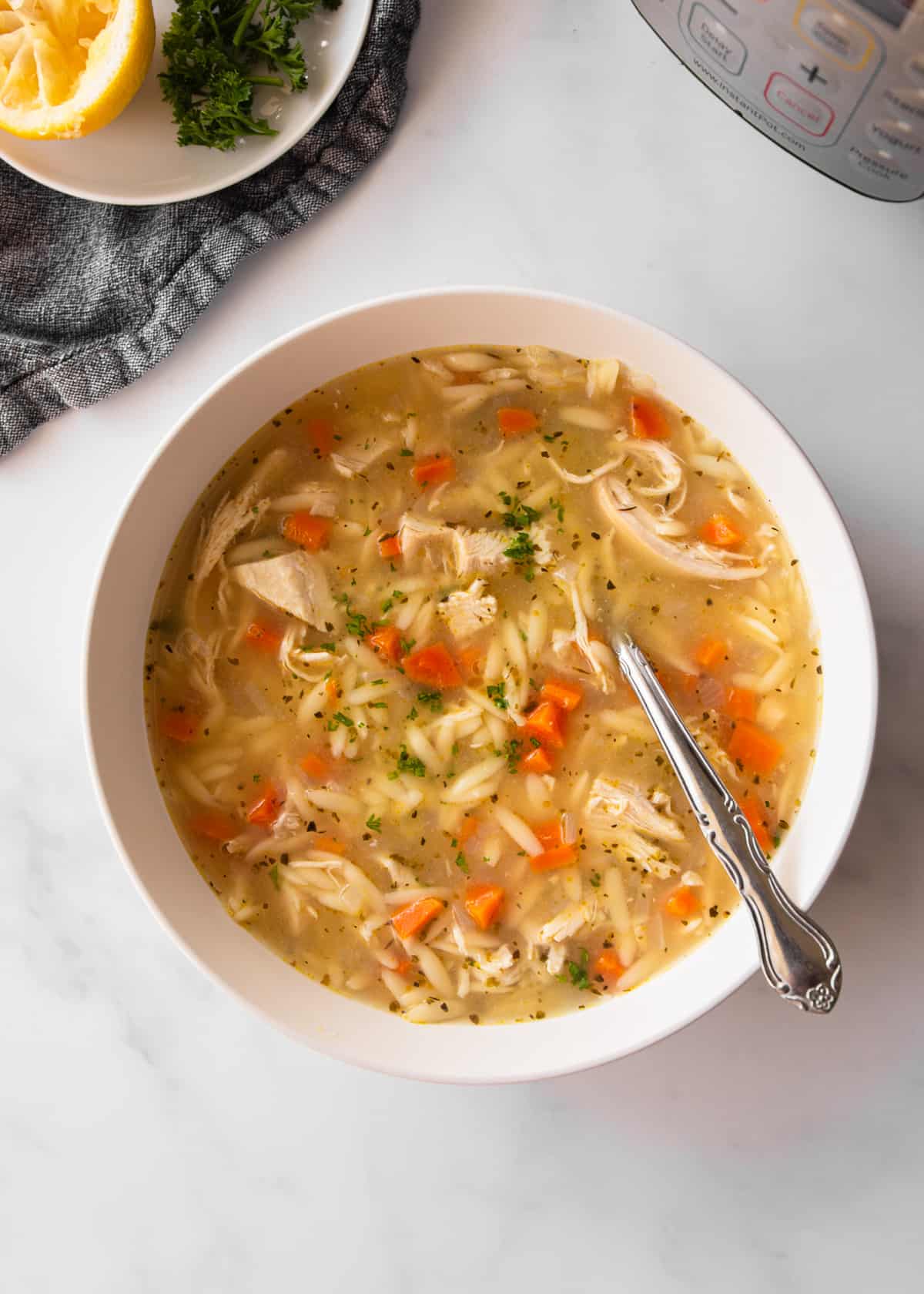 a bowl of chicken and orzo soup on a grey countertop