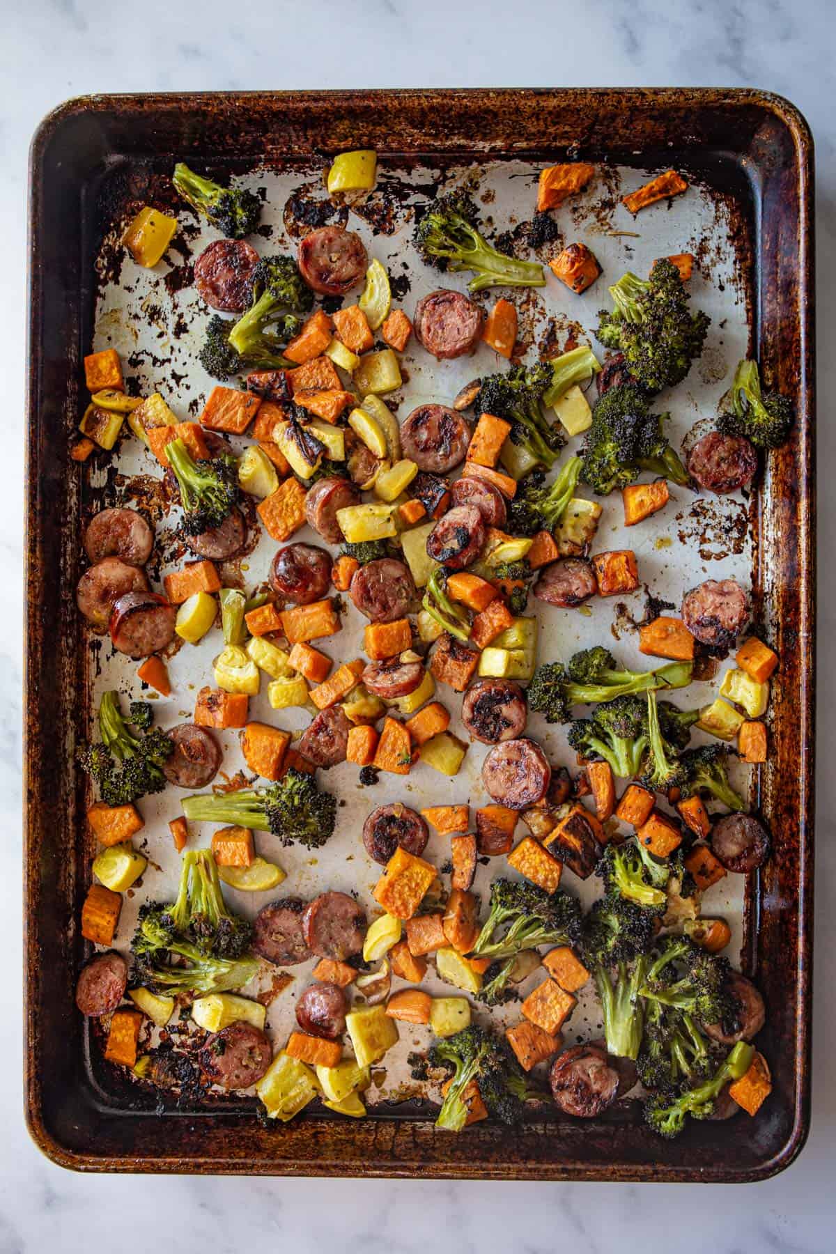 overhead image of cooked sausage and vegetables on a sheet pan