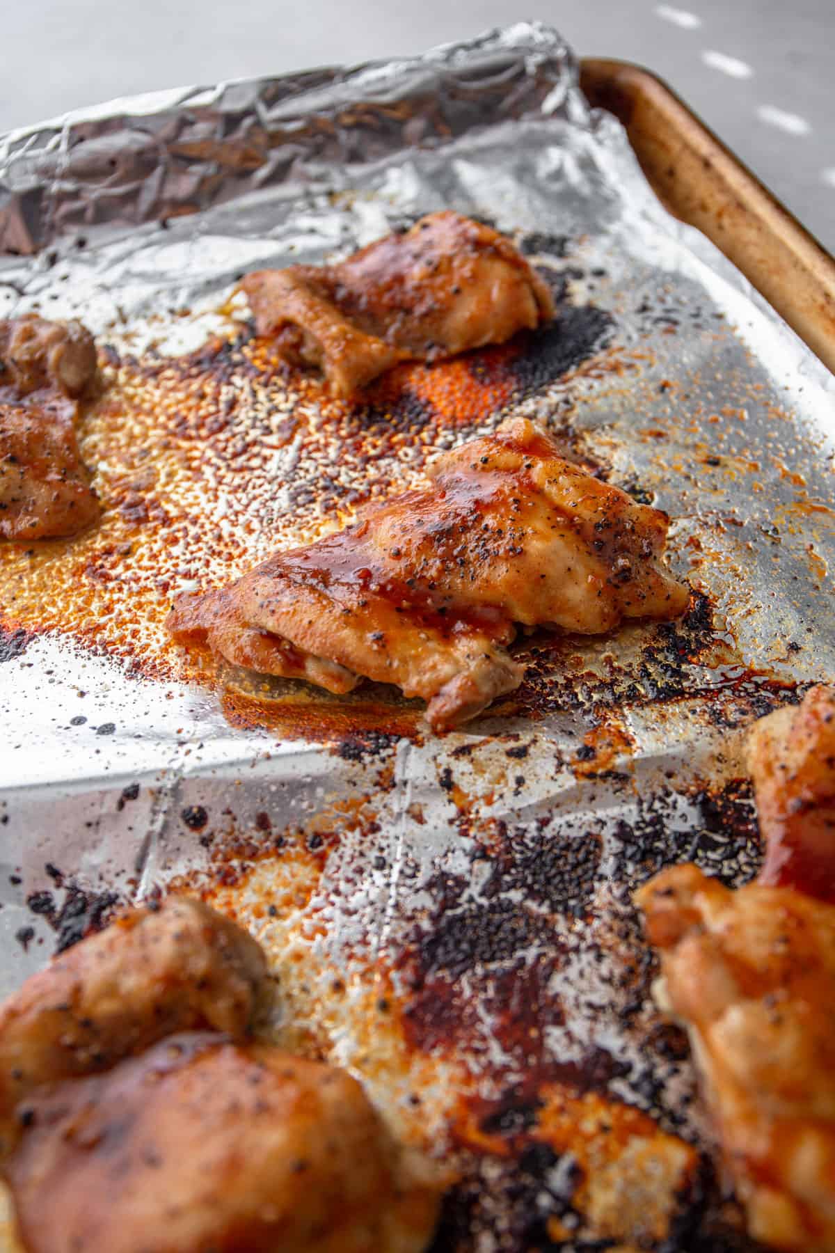 cooked glazed chicken pieces on a foil lined sheet pan