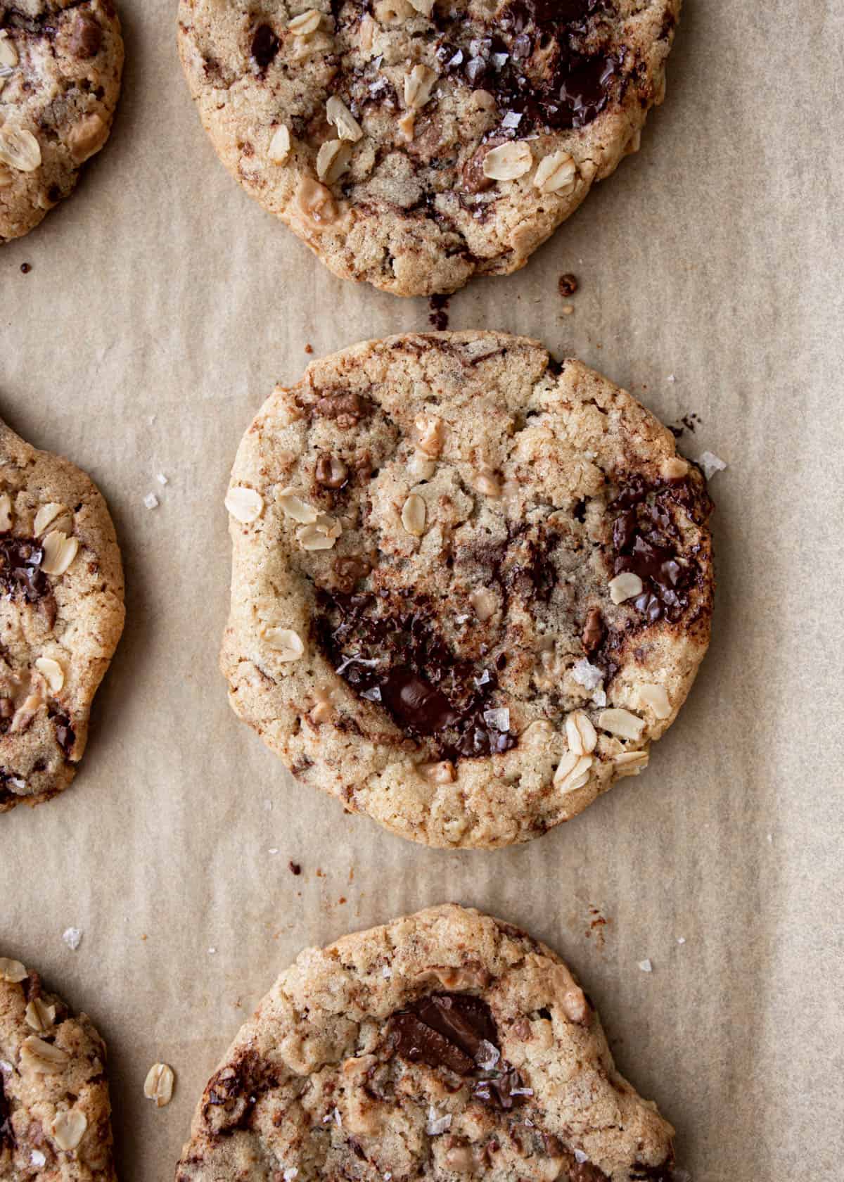 close up image of oatmeal and chocolate cookies on a parchment lined sheet pan
