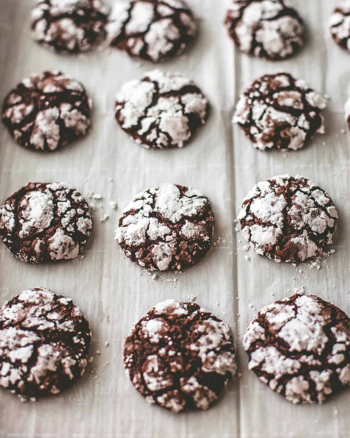 chocolate crinkle cookies on a parchment lined sheet pan