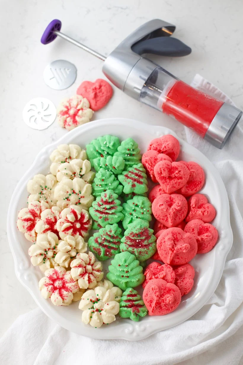spritz cookies and cookie press on a white countertop