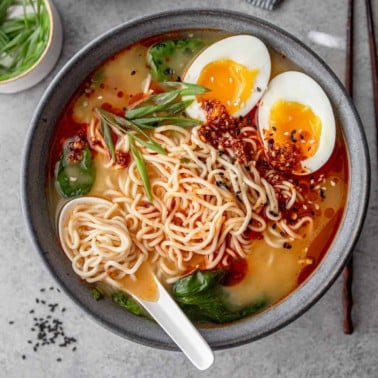 a bowl of ramen with a spoon and a soft boiled egg
