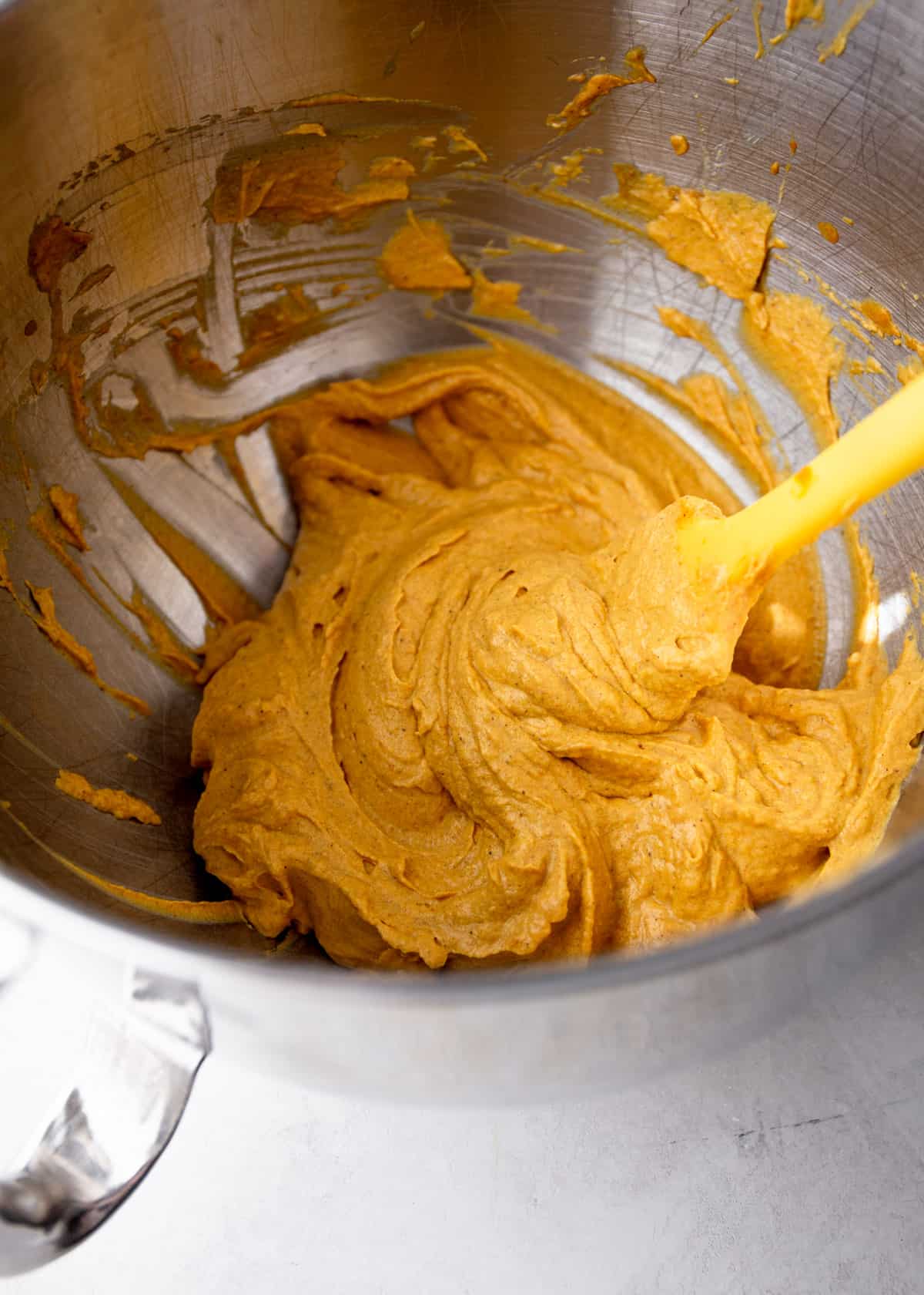 stirring pumpkin mixture in a large silver mixing bowl