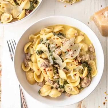 sausage and kale pasta in a white bowl