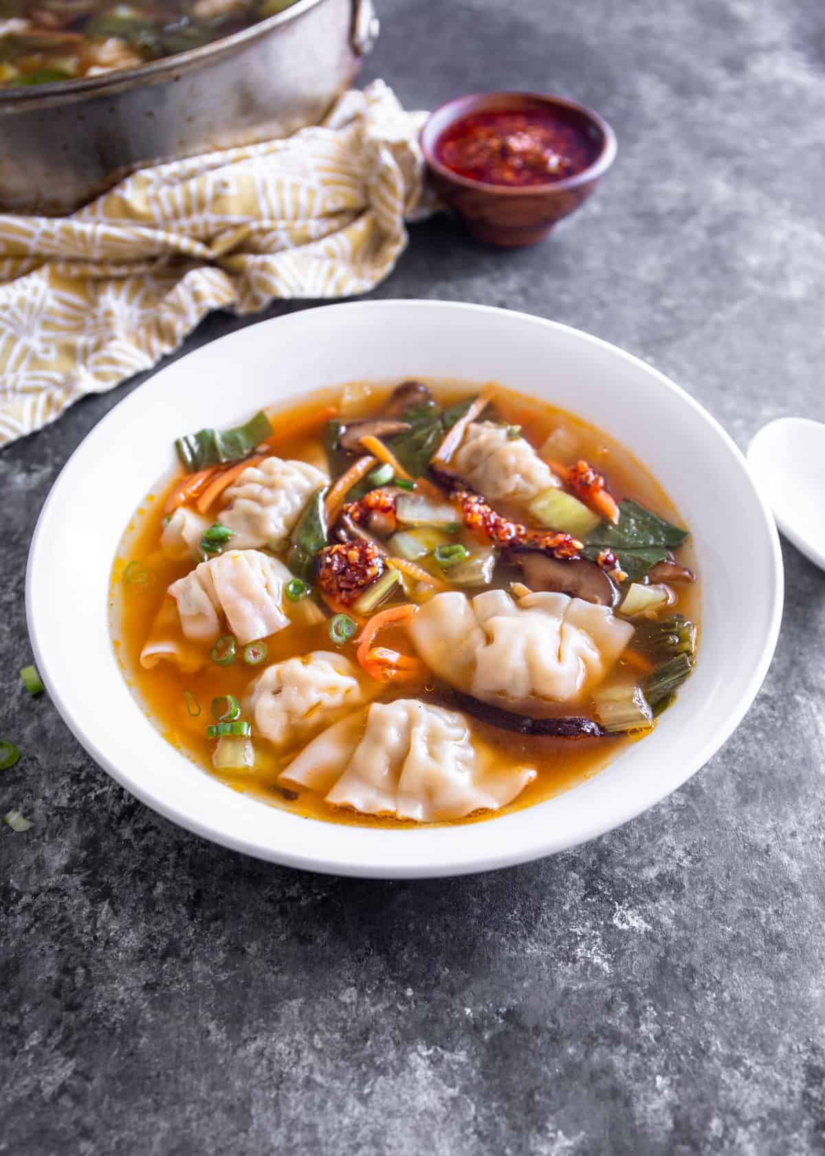 wonton soup in a white bowl on a grey countertop