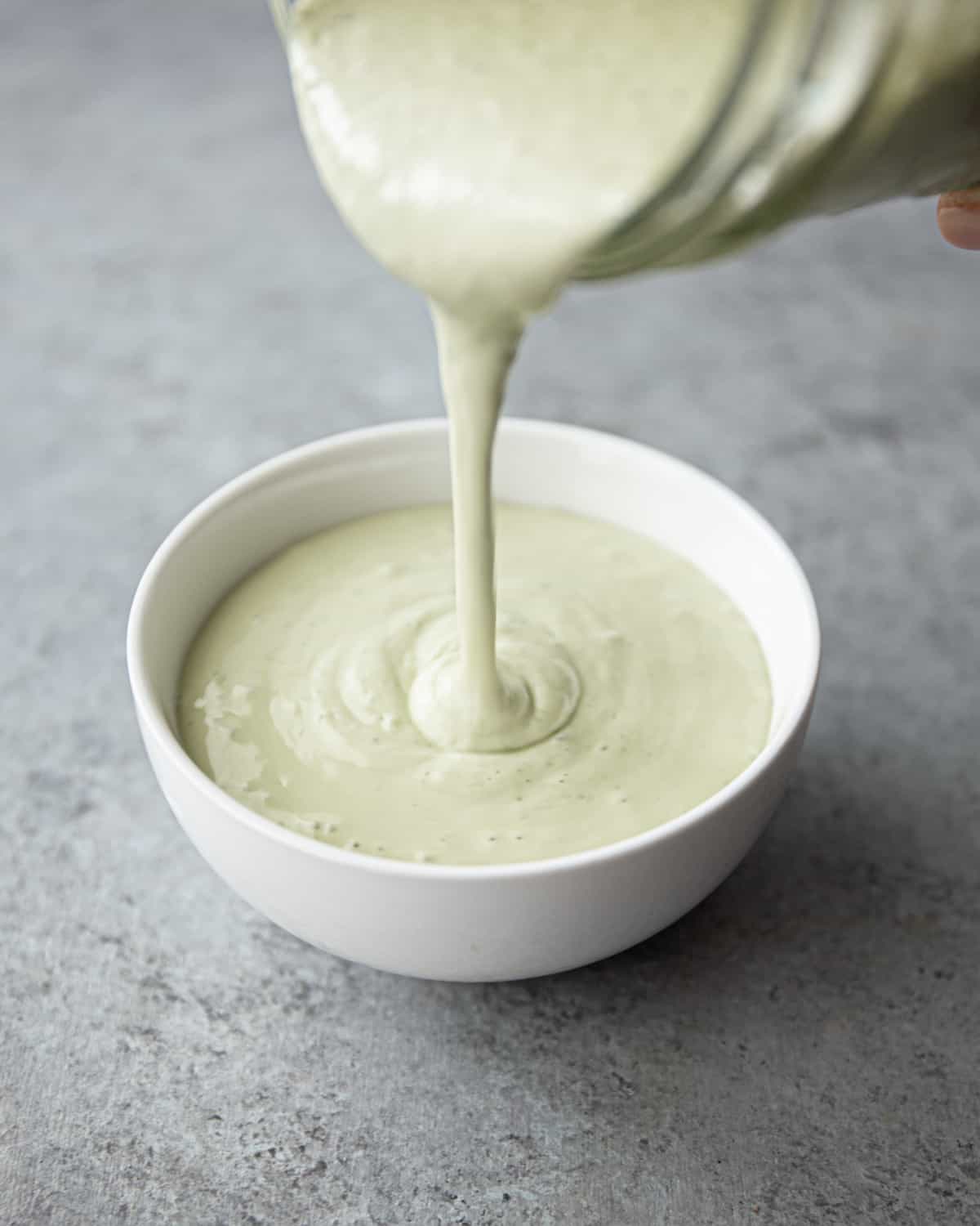 pouring dressing into a small white bowl