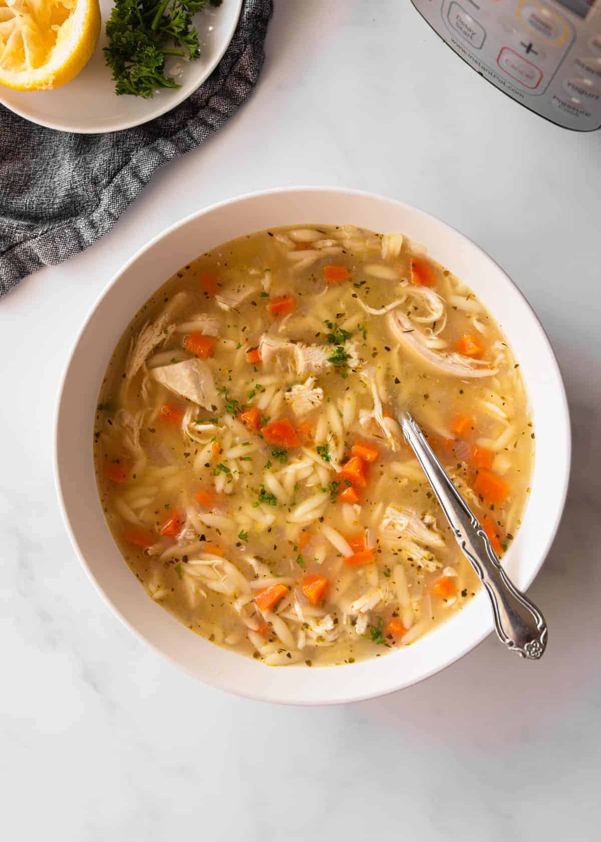 chicken and orzo soup in a white bowl on a grey table