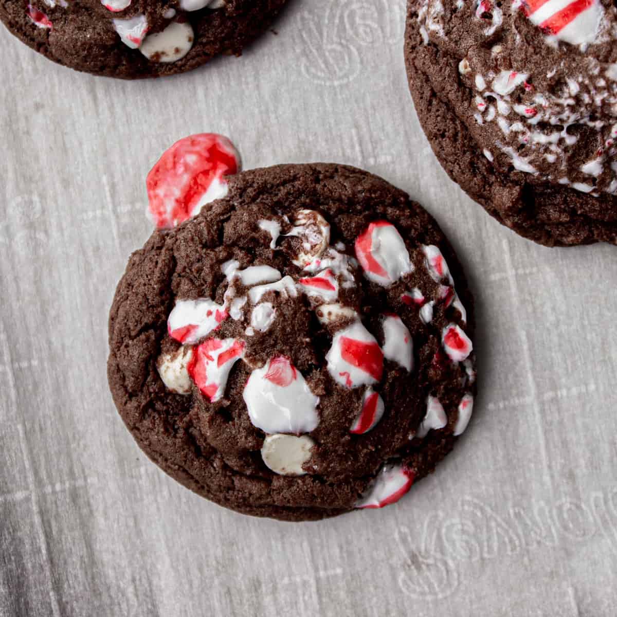 overhead image of a chocolate cookie with peppermint pieces on a parchment lined sheet pan