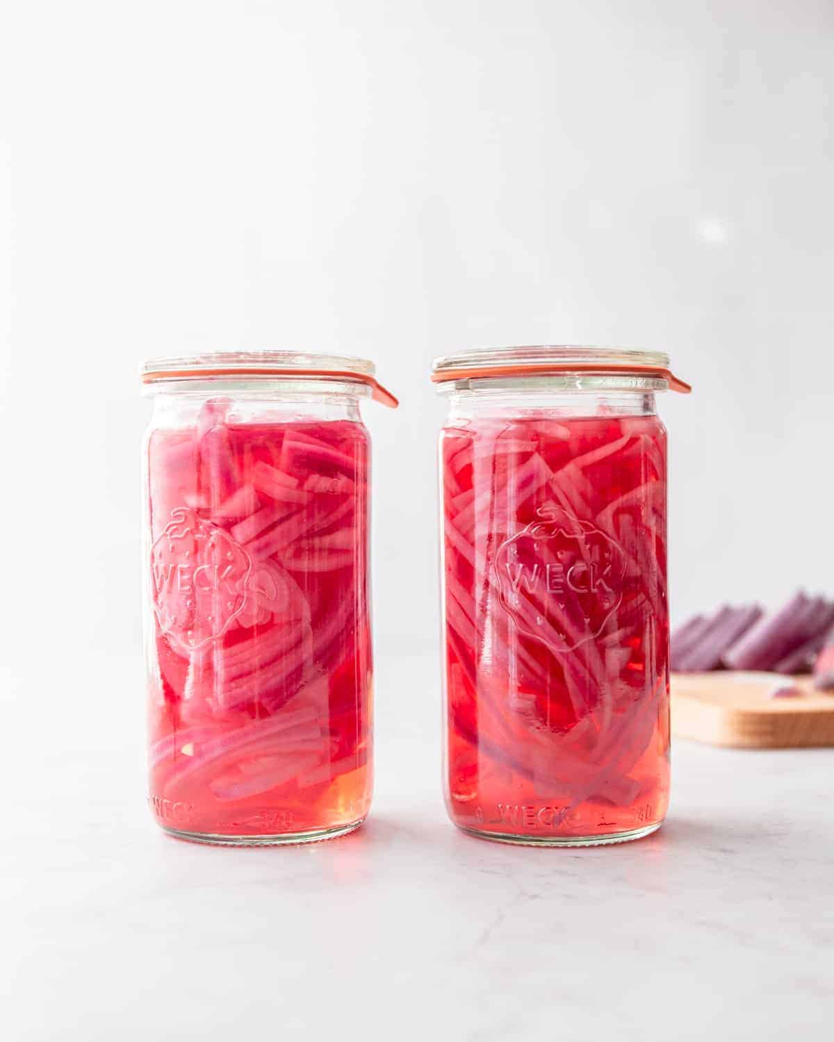 pickled red onions in glass jars on a grey countertop