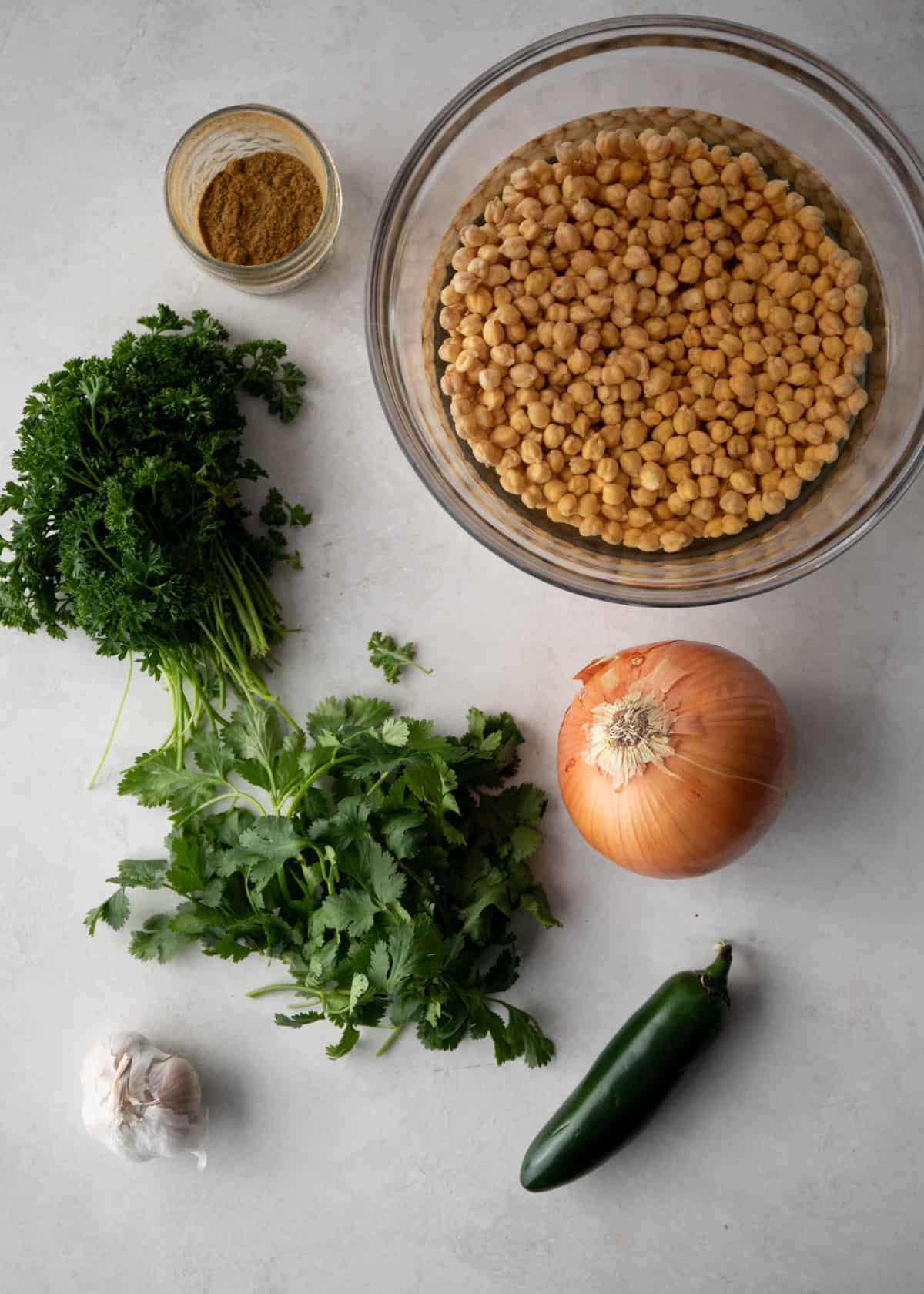 overhead image of all the ingredients for falafel spread out on a grey countertop
