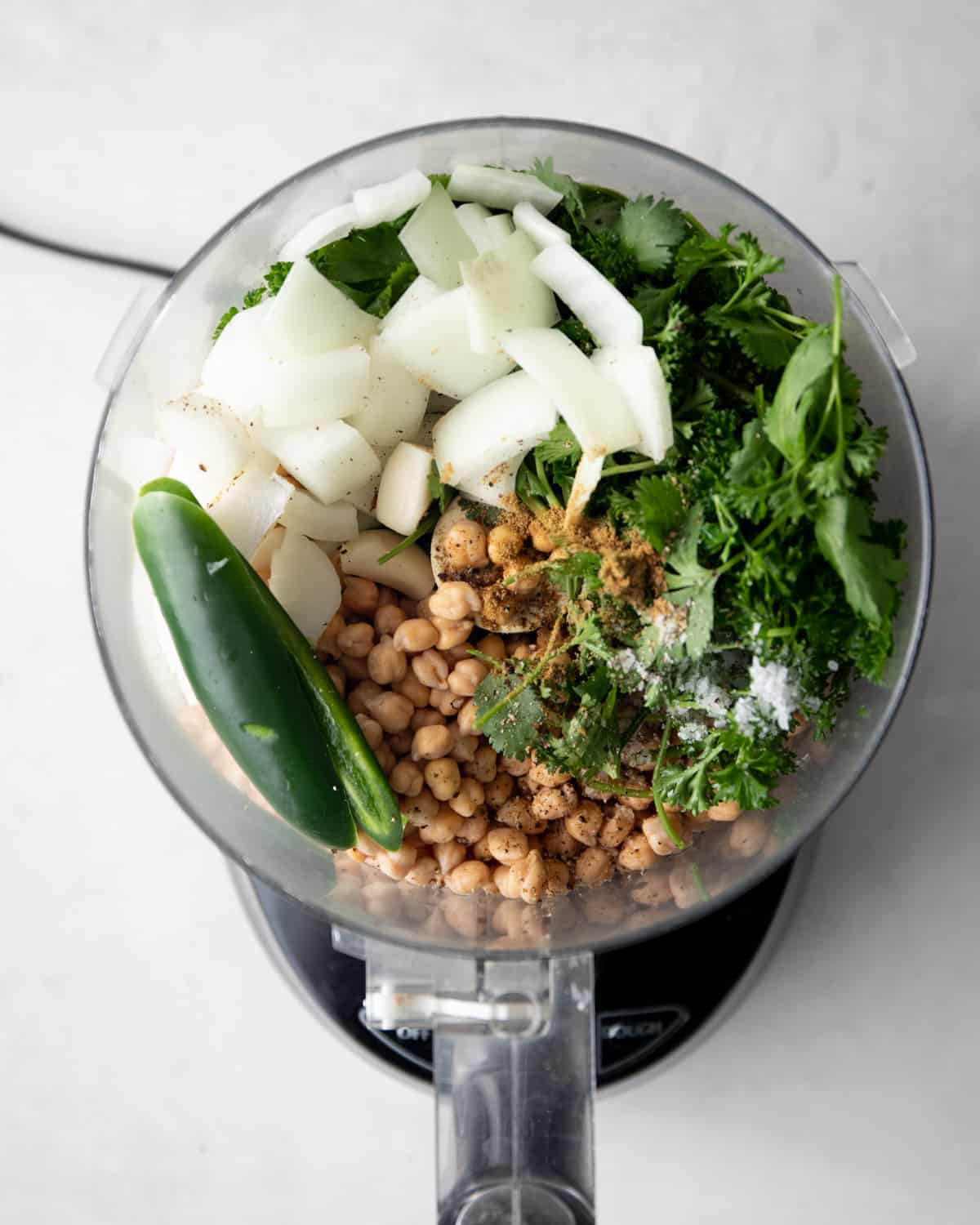 overhead image of ingredients for falafel in the bowl of a food processor