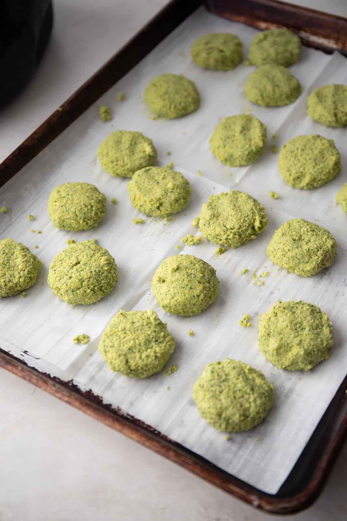 raw falafel patties on a parchment lined sheet pan