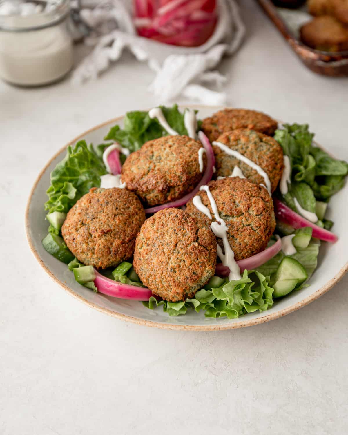 falafel on tope of a green salad in a white bowl