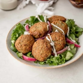 falafel on top of a green salad in a white bowl