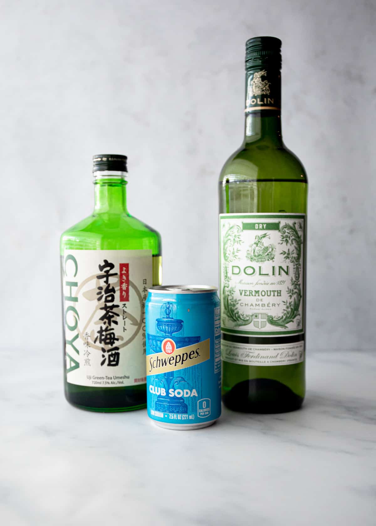 bottles of umeshu, vermouth and club soda on a grey countertop