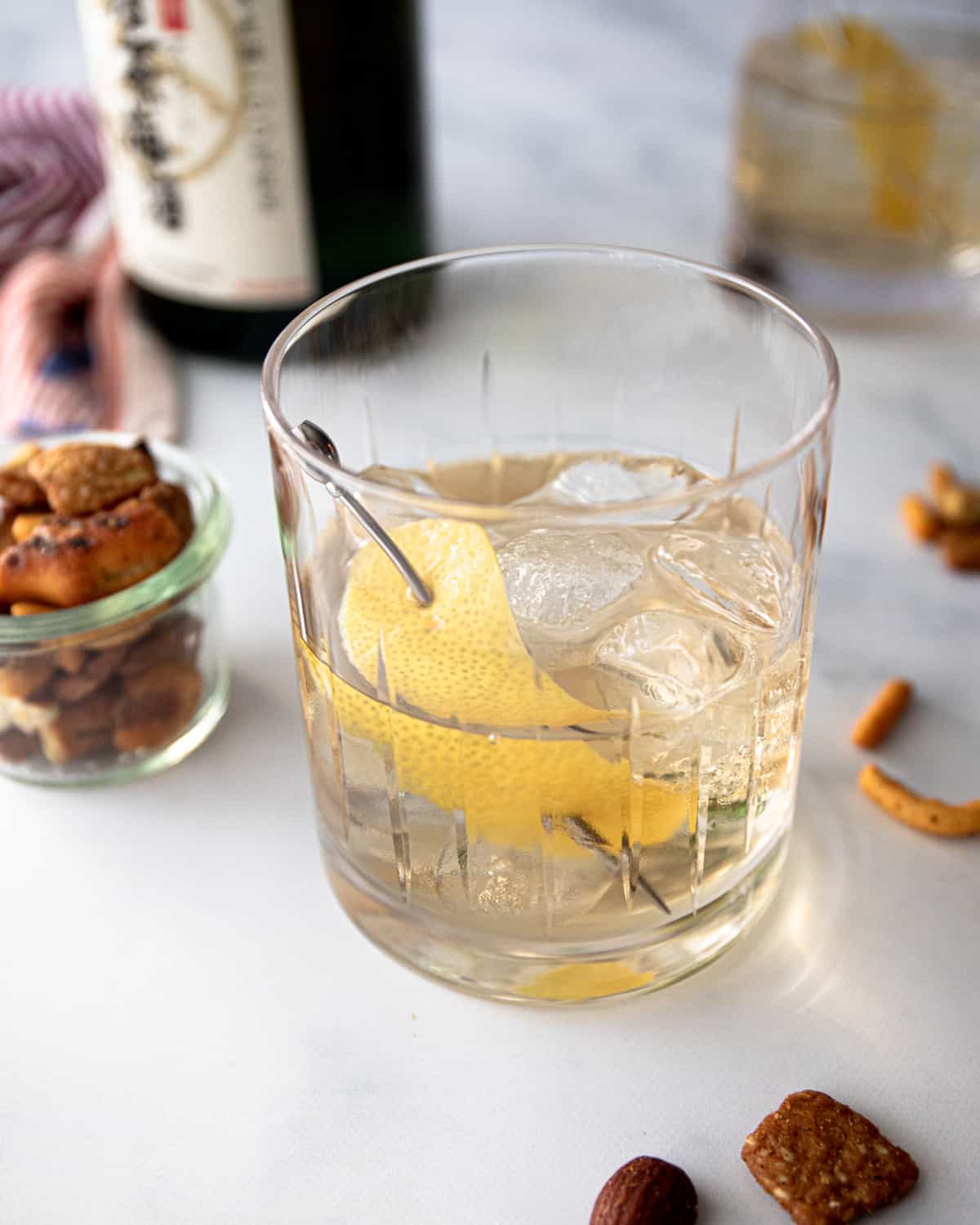 an overhead image of a green tea cocktail with a lemon twist garnish on a grey countertop