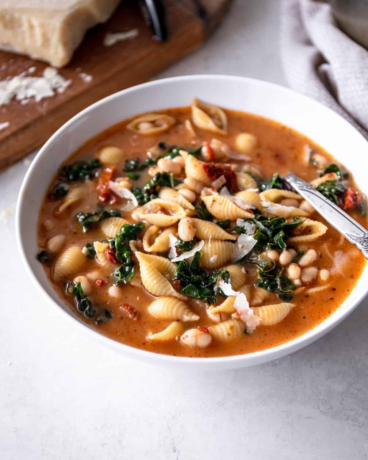 tuscan kale and white bean soup in a white bowl with a spoon