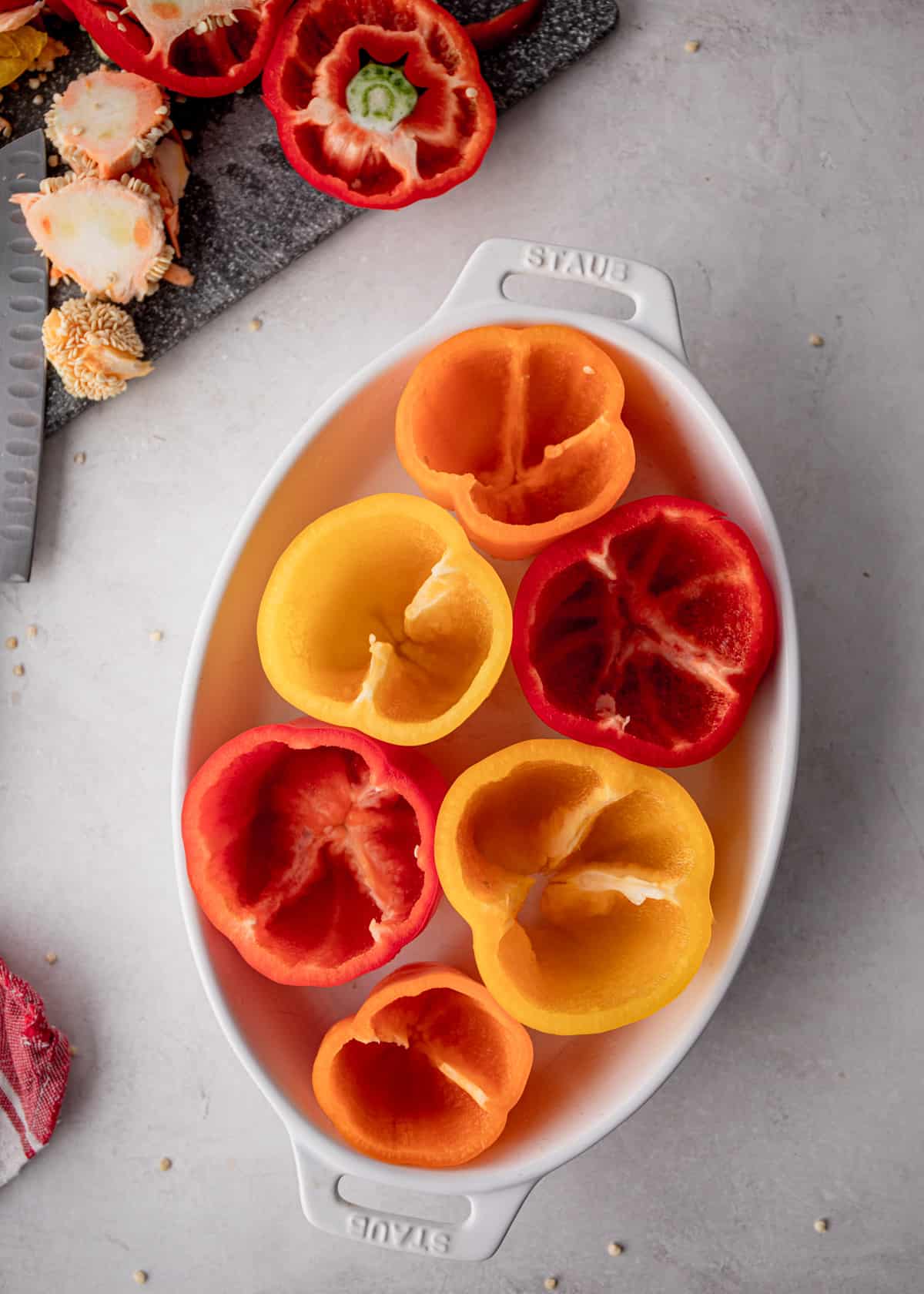 raw hollowed out bell peppers in a white oval baking dish