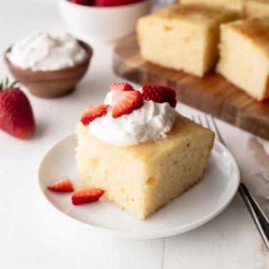 vanilla semolina cake on a white plate with strawberries and cream