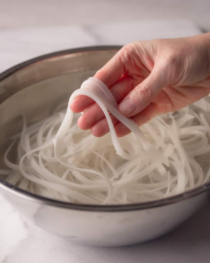 soaking pad thai noodles in a metal bowl