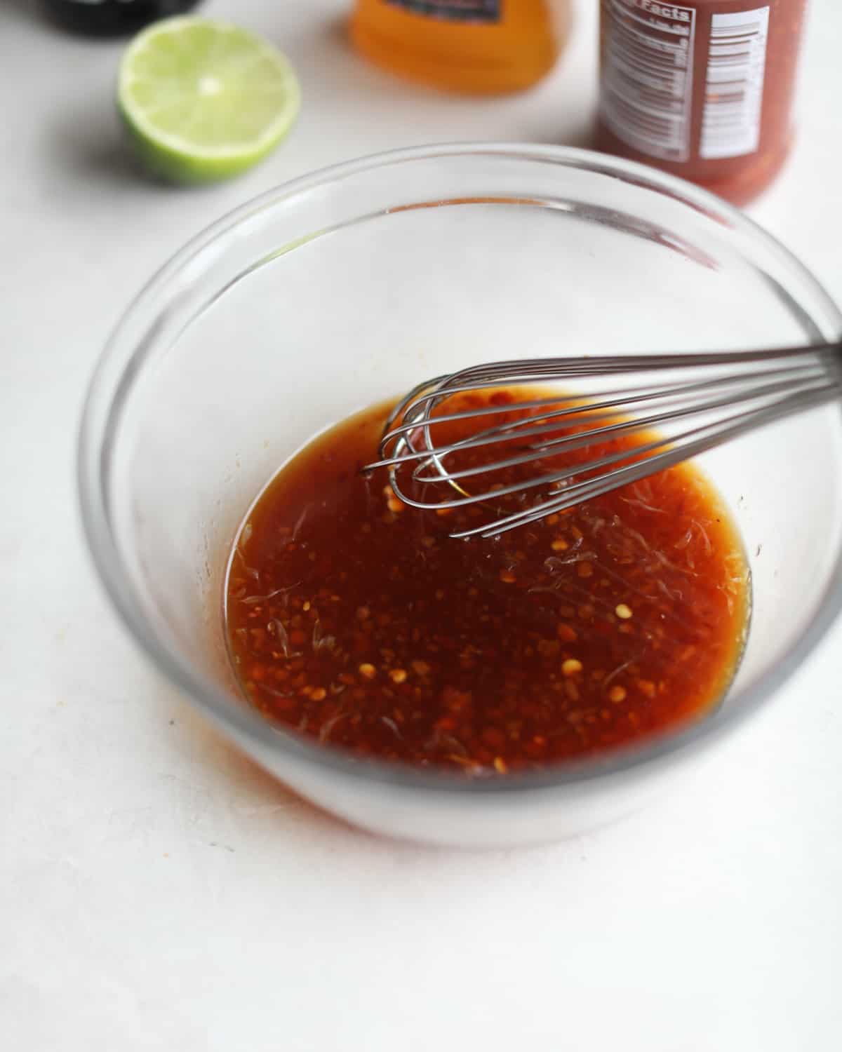 stirring sauce with a whisk in a clear glass bowl
