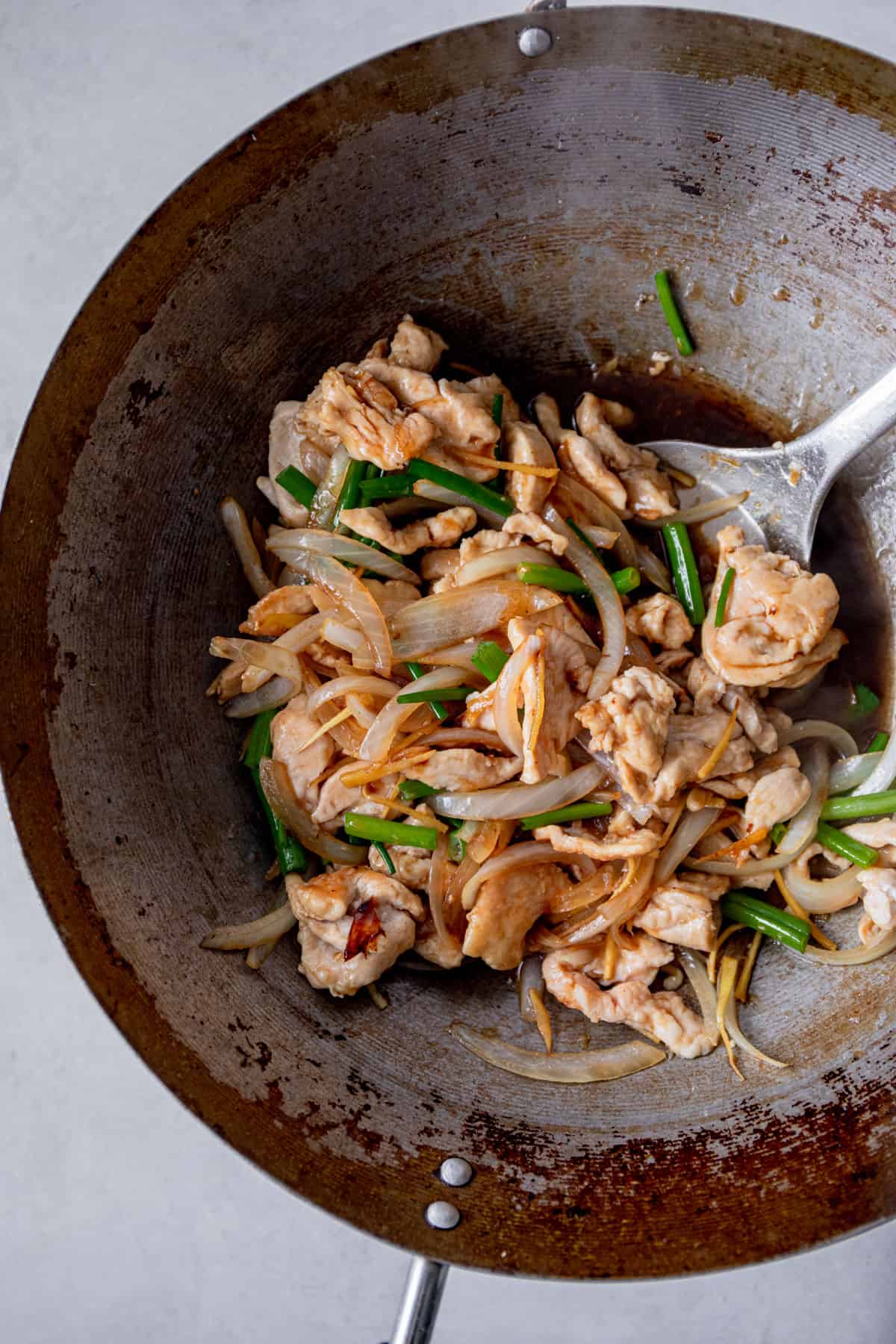ginger chicken, onions and sauce in a wok