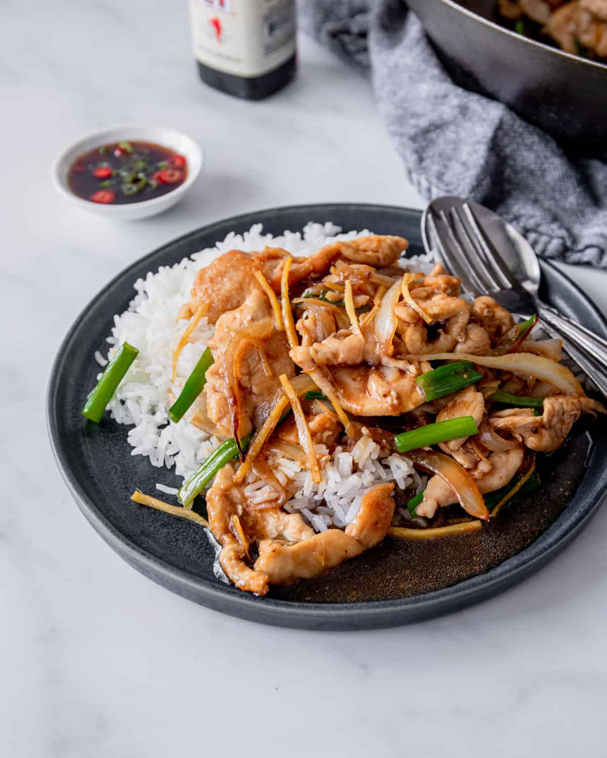 thai ginger chicken over rice on a black plate