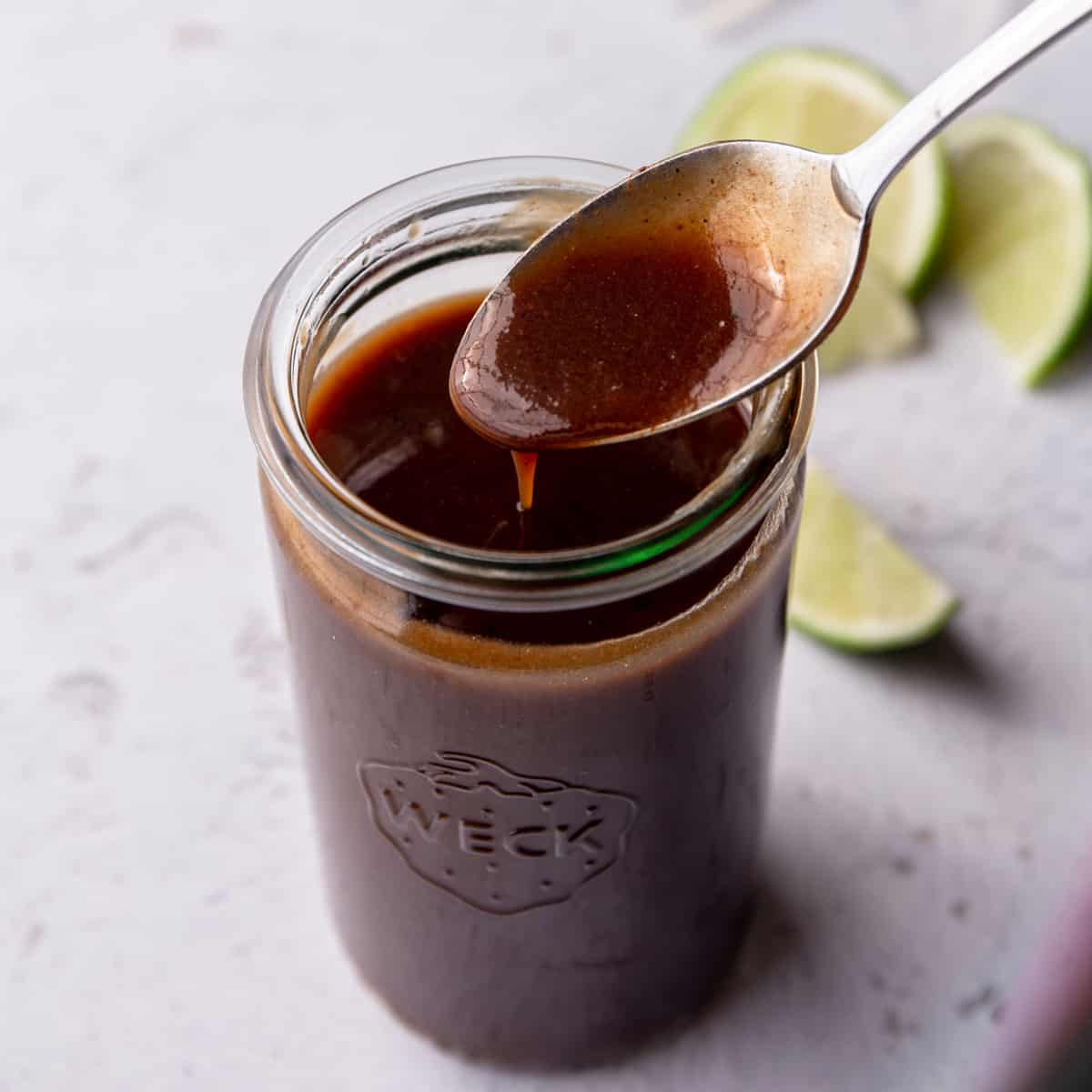 glass jar of dark red sauce with a spoon