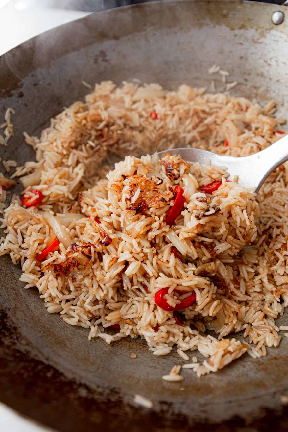 mixing rice with peppers and onions in a wok