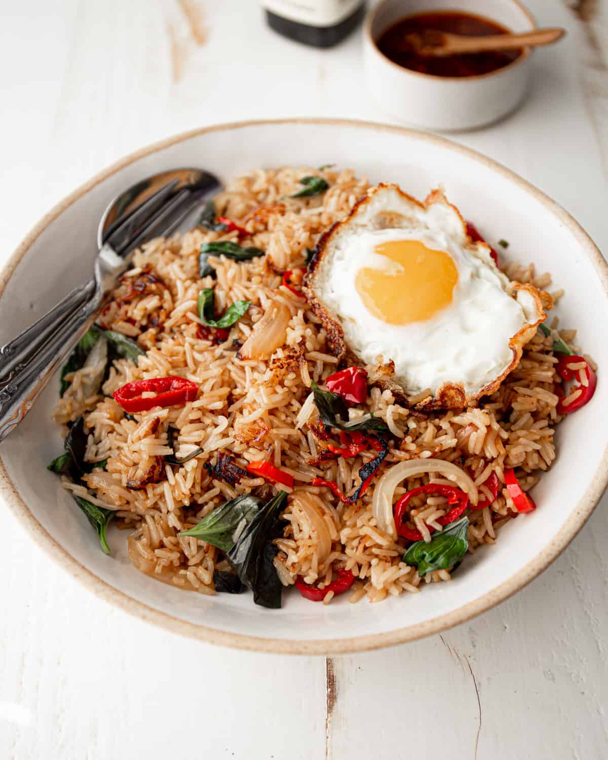 fried rice in a white bowl topped with a fried egg