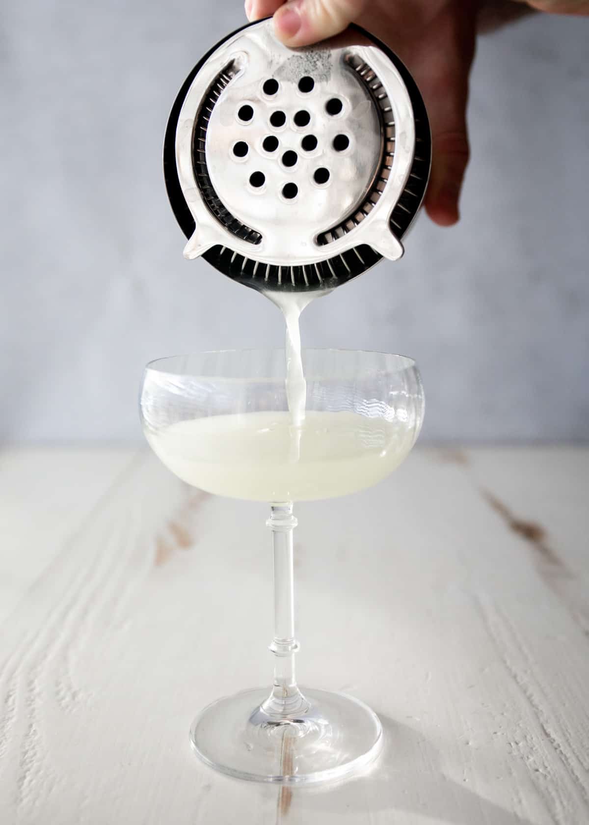 pouring last word cocktail into a glass