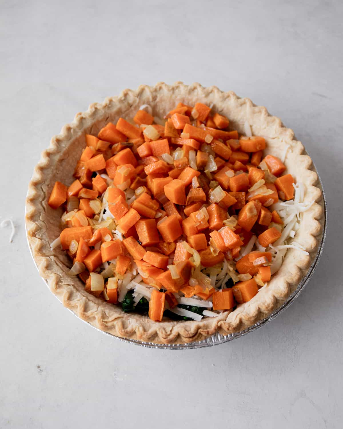 overhead image of adding vegetables to a pie crust