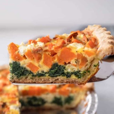 removing a piece of vegetable quiche from a pie plate