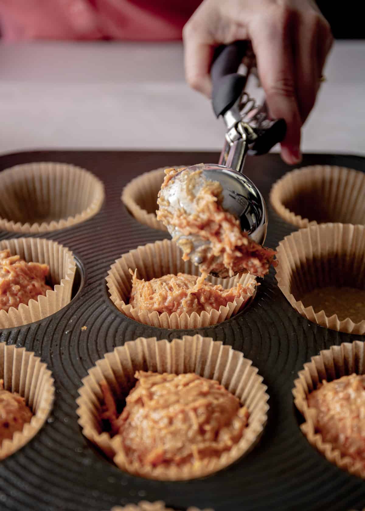 adding muffin mixture to lined muffin pan