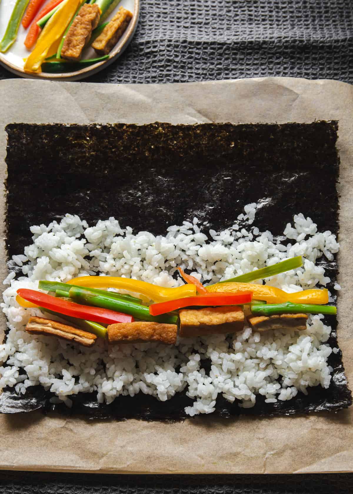 rolling vegetarian sushi on a piece of parchment paper