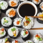 chopsticks holding a piece of vegetarian sushi over a white tray