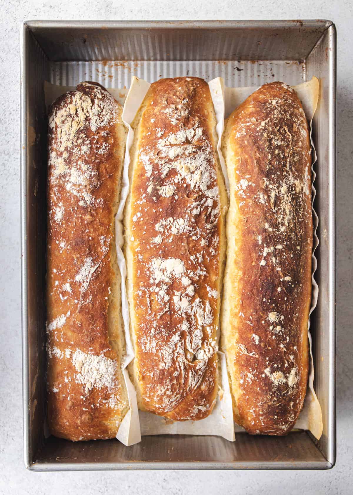 3 baked loaves of French bread in a metal baking pan