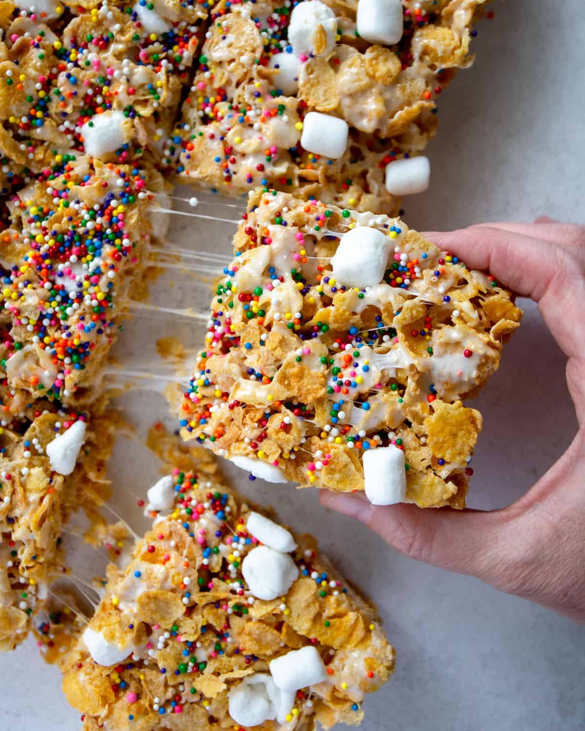 removing a slice of marshmallow cornflake treat from a sheet pan
