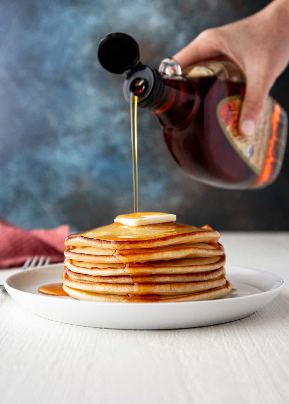pouring syrup on a stack of greek yogurt pancakes