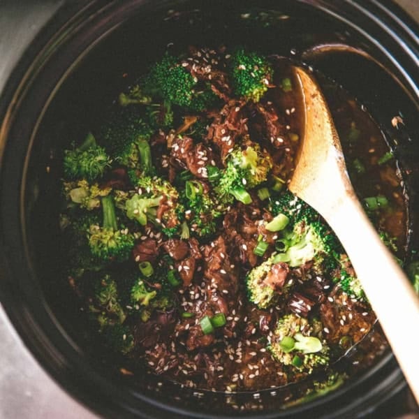 round black slow cooker bowl filled with sesame beef and broccoli florets